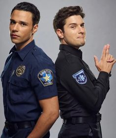 two men in police uniforms standing next to each other with their hands on their hips