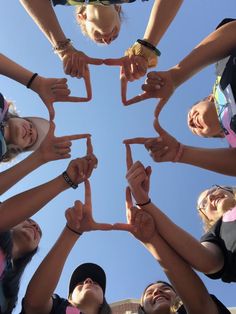 a group of young people standing in a circle making the shape of a heart with their hands