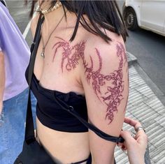 a woman with tattoos on her arm and shoulder is walking down the street in front of some people