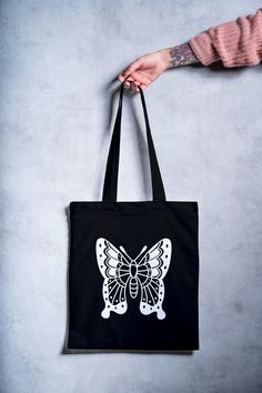 a person holding a black bag with a white butterfly on it