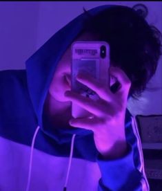 a young man taking a selfie with his cell phone while wearing a hoodie