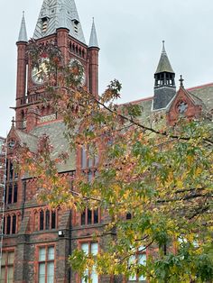 an old brick building with a clock tower on it's side and trees in front