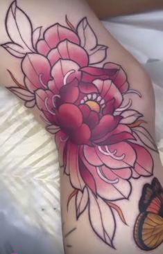 a woman's leg with a flower and butterfly tattoo design on it, sitting on a bed