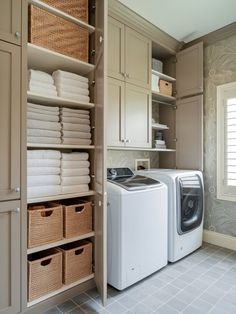 a washer and dryer in a small room with lots of linen on the shelves