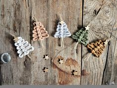 three small knitted christmas trees sitting on top of a wooden table next to other ornaments