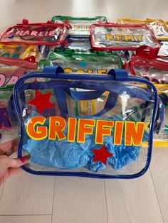 a hand is holding a clear bag with the word griffin written on it in front of other plastic bags