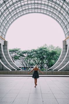 a woman in a black dress is walking through an arch