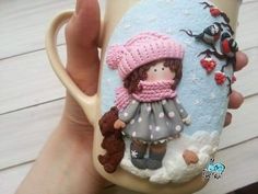 a hand holding a coffee cup with a doll on it