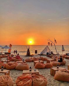 the sun is setting on the beach with bean bag chairs set up in front of it