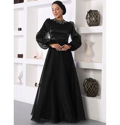 Modest Formal Satin Dress G531 Black ATTENTION: This item has a special return policy, different from our regular store policy. See details below. A classy evening dress perfect for formal events! Features a gemmed petal design along the neckline, puffed sleeves, and is made with sleek satin. FEATURES: - Fully lined - Satin fabric with organza overlay - Gemmed petal design along neckline - Puffed sleeves with a small flare at the wrist - Matching satin waistband with glitter along sides FABRIC Satin fabric made from 100% Polyester. Weighs about 2 lbs CARE: Dry clean only Do not machine wash Do not machine dry Do not bleach Made in Turkey SPECIAL RETURN POLICY FOR EVENING GOWNS The following return policy applies on all evening gowns: • Return must be requested within 48 hours of receiving Elegant Embellished Black Dresses, Elegant Embellished Dresses For Banquet, Elegant Satin Gown With Sequins, Black Embellished Maxi Dress For Banquet, Formal Embellished Satin Dresses, Black Embellished Maxi Dress For Wedding, Formal Satin Sequin Dress, Black Embellished Satin Dress, Formal Satin Dress