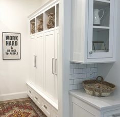 a kitchen with white cabinets and rugs on the floor