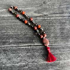 The Root Chakra Intention Bracelet, made with Red Jasper, Smoky Quartz, and Hematite, is designed to help you feel grounded and balanced. Use this piece to instill a sense of stability, strength, and security. Materials: 8mm Red Jasper, Smoky Quartz, and Hematite beads 12x18mm Rhodonite focal stone brown C-lon thread 1.25" deep red silky tassel silver plated accent beads Every bead is lovingly strung on thread and hand-knotted between each stone, embodying the essence of patience and devotion. Y