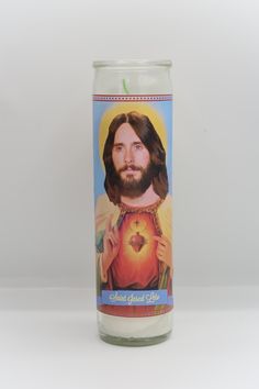 a candle with the image of jesus holding an apple in it's center, on a white background