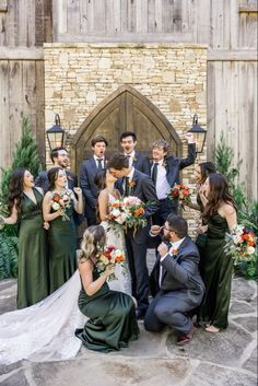 a group of people standing next to each other in front of a wooden door with flowers