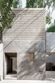 a concrete building with an open door on the side and trees in the back ground