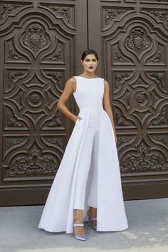 a woman in a white dress standing next to a wooden door with the words jane jumpsuit