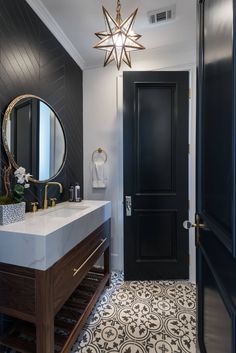 a black and white bathroom with a star shaped light hanging over the sink, along with a large mirror on the wall