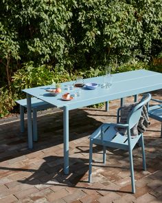 a blue table and two chairs on a brick patio