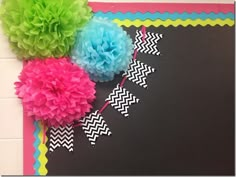 tissue pom poms and streamers on a bulletin board