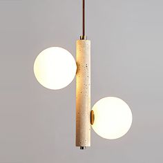 two lights that are hanging from the ceiling in front of a gray wall and floor