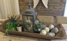 a wooden tray filled with plants and rocks on top of a table next to a lantern