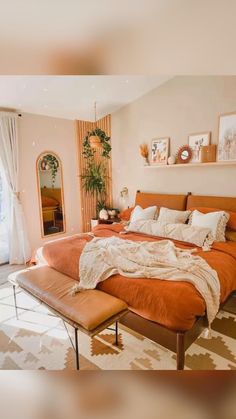 a bedroom with an orange bed, mirror and plant on the wall next to it