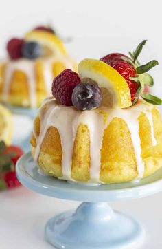 a lemon bundt cake with icing and fruit on top, sitting on a blue plate