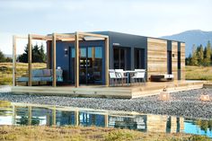 a small house sitting on top of a grass covered field next to a body of water