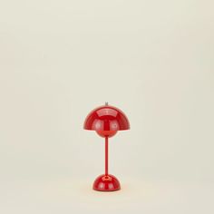 a red table lamp sitting on top of a white floor