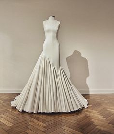 a dress made out of white paper sitting on top of a wooden floor