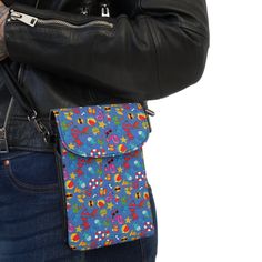 a woman wearing a black leather jacket is holding a blue and multicolored purse