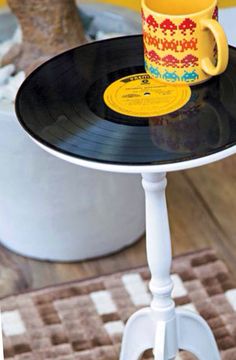 an old record table with a coffee cup on it and a yellow mug sitting on top