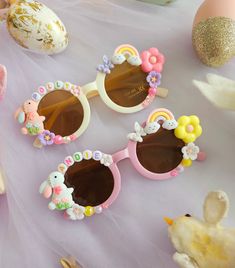 three pairs of sunglasses decorated with flowers and bunny ears on top of a pink tablecloth