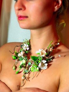 a woman wearing a necklace with flowers and leaves attached to it's neckline