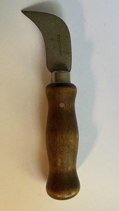 an old style knife stuck in the side of a wooden handle on a white wall