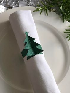 a white plate topped with a green napkin and a christmas tree on top of it