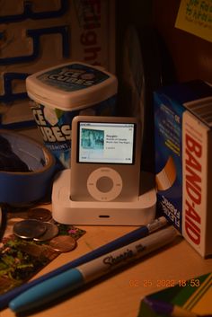 an ipod sitting on top of a wooden table next to some pens and other items