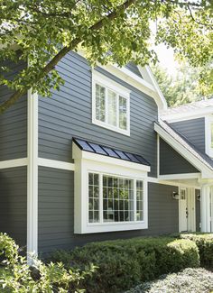 a gray house with white trim on the front and side windows is seen in this photo