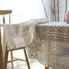 a table with a white crochet doily on it next to a wooden chair