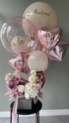 a bunch of balloons that are on top of a table with some flowers in it