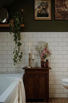 a white toilet sitting next to a bath tub in a bathroom under two framed pictures