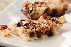 two pieces of dessert sitting on top of a white plate with nuts and raisins