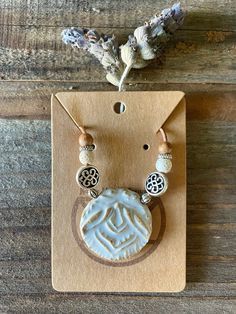 a necklace and earring set sitting on top of a piece of wood next to a dried plant