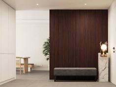 an empty room with a bench, table and plant on the wall next to it