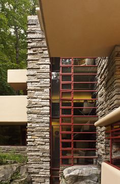 an exterior view of a house with stone walls and red metal stairs leading up to the front door