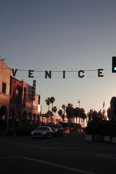 cars are parked on the street in front of an old building and palm trees at sunset