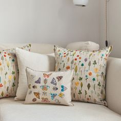 a white couch with four pillows on it and a lamp in the corner behind it