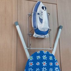 an ironing board with a blue and white iron on it next to a wooden door