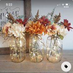 three mason jars filled with flowers and fairy lights