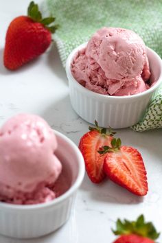 two bowls filled with ice cream next to strawberries